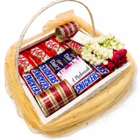 Eid Gift Basket For Her – A beautiful basket filled with Snickers, KitKat, Dairy Milk, Twix, bangles, and fresh flowers, perfect for Eid gifting.